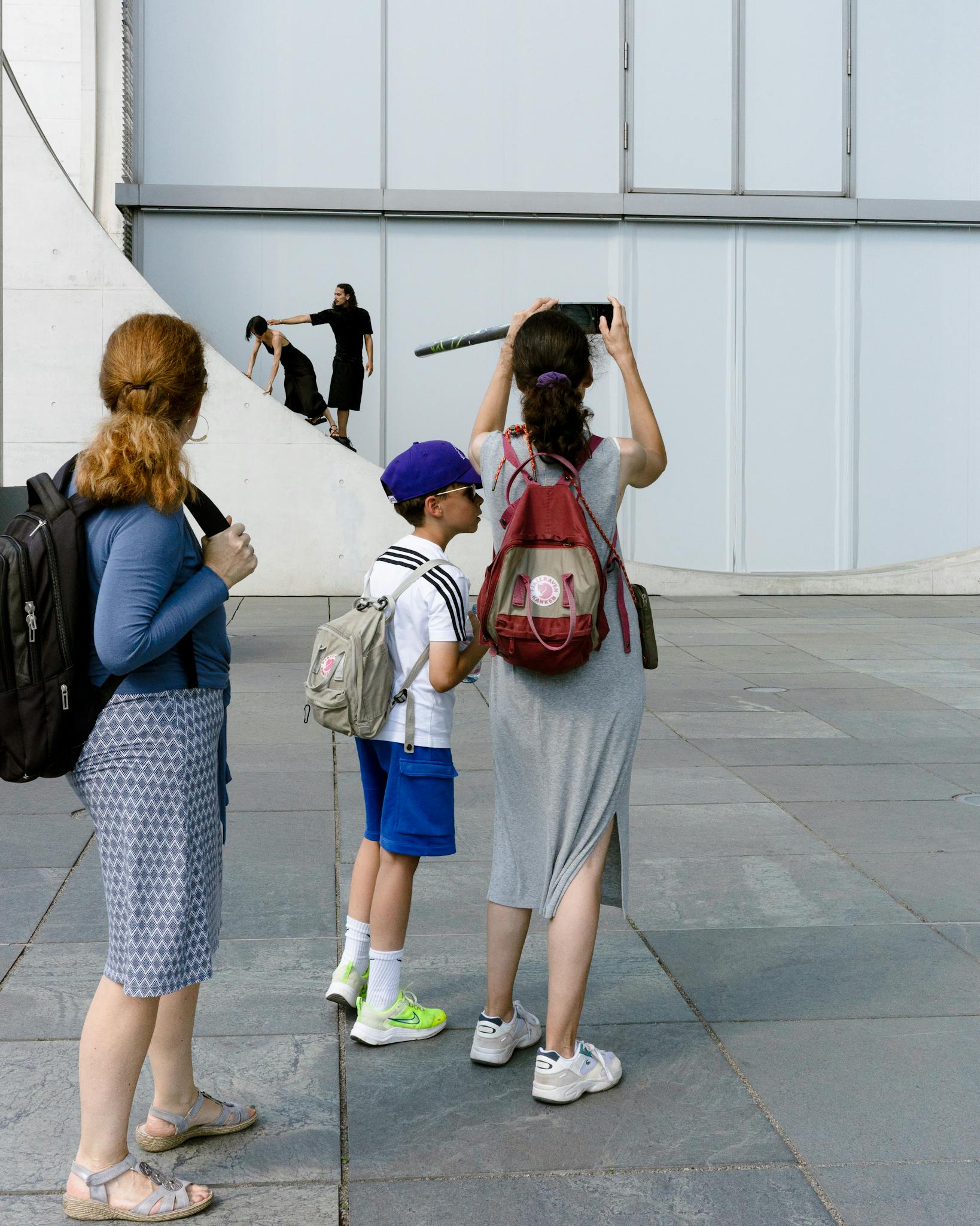 Group of tourists photographing a modern building in the city, showcasing urban exploration.