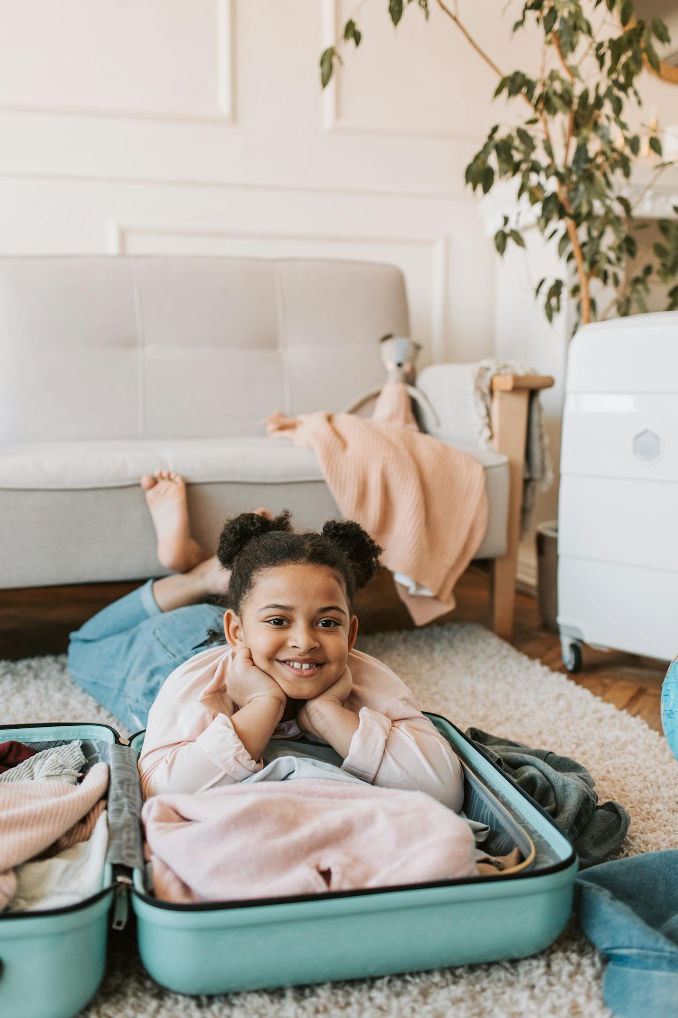 Joyful child lying in suitcase, preparing for travel adventure with a smile.